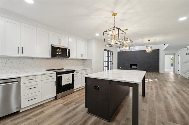 kitchen featuring light hardwood / wood-style flooring, stainless steel appliances, a center island, decorative light fixtures, and white cabinets