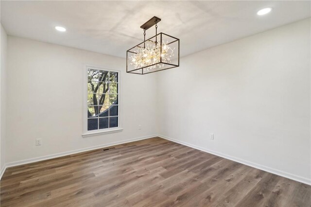 unfurnished dining area featuring a chandelier and wood-type flooring