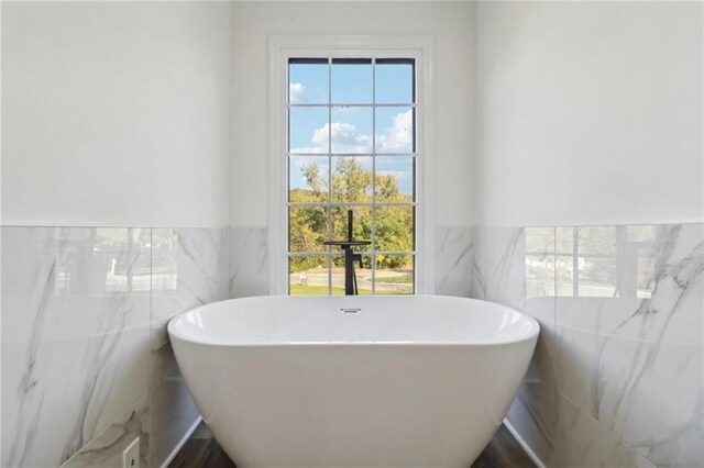 bathroom with tile walls, wainscoting, and a wealth of natural light