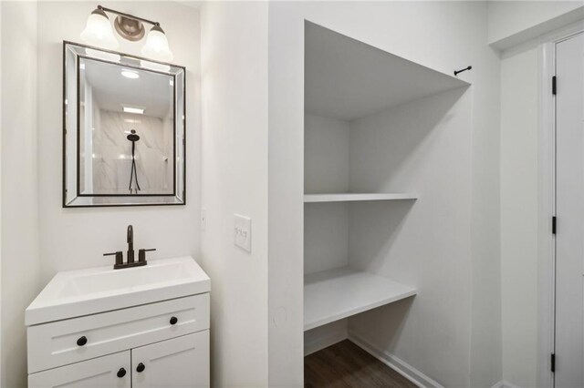 bathroom with wood finished floors, a shower, and vanity