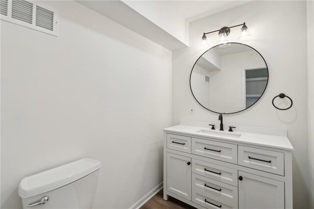 bathroom with vanity, toilet, and hardwood / wood-style floors