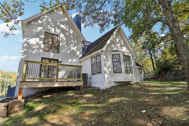 rear view of house featuring a chimney, central AC unit, a shingled roof, and a wooden deck