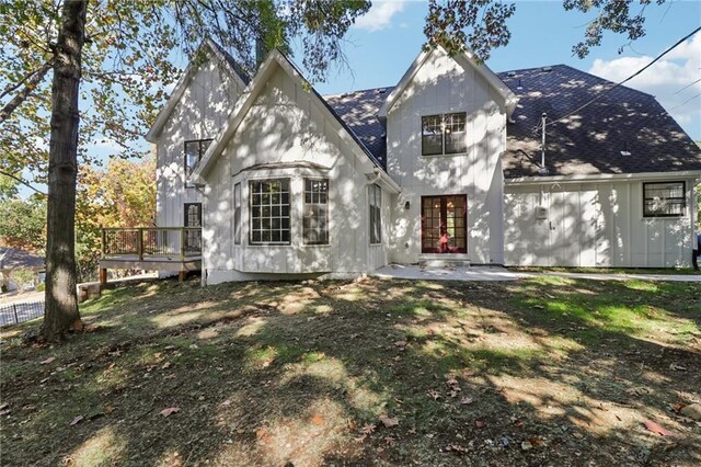 tudor home with a shingled roof, a patio area, french doors, and a wooden deck