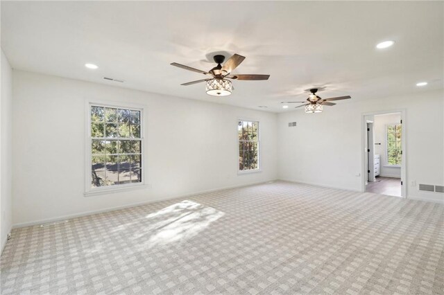 carpeted spare room featuring ceiling fan and a wealth of natural light