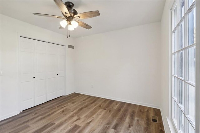 unfurnished bedroom with a closet, dark hardwood / wood-style floors, and ceiling fan