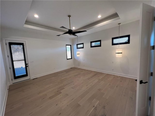 spare room featuring light hardwood / wood-style floors, a tray ceiling, a wealth of natural light, and ceiling fan