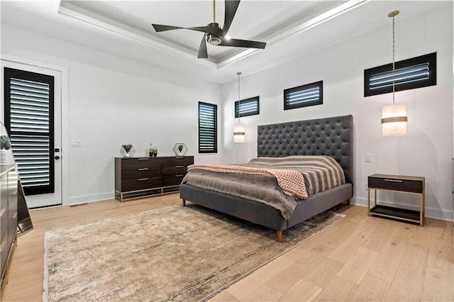 bedroom with a raised ceiling, light hardwood / wood-style floors, and ceiling fan