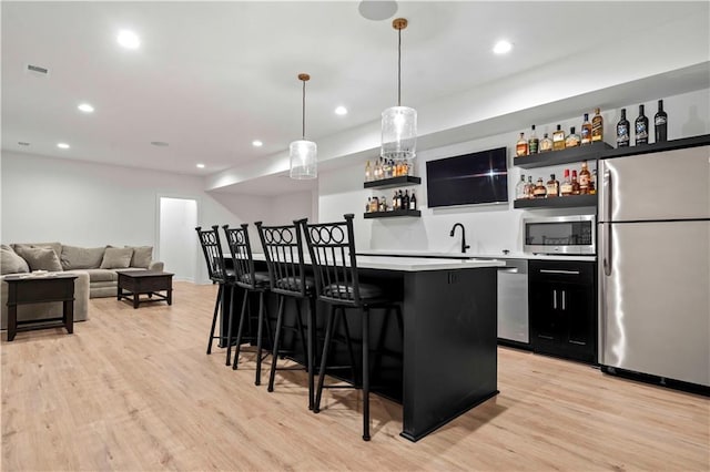 kitchen with a kitchen island, light hardwood / wood-style floors, stainless steel appliances, and a breakfast bar