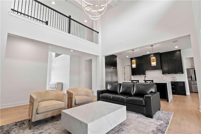 living room featuring a towering ceiling, light hardwood / wood-style floors, and a notable chandelier