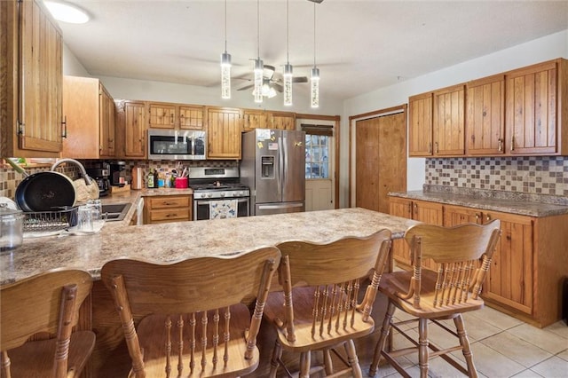 kitchen with ceiling fan, pendant lighting, kitchen peninsula, appliances with stainless steel finishes, and decorative backsplash