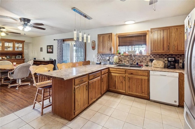 kitchen with sink, kitchen peninsula, hanging light fixtures, a kitchen breakfast bar, and white appliances