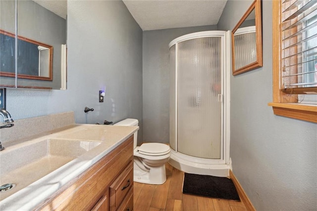 bathroom with hardwood / wood-style floors, a shower with shower door, vanity, and toilet