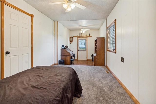 carpeted bedroom featuring ceiling fan and a textured ceiling