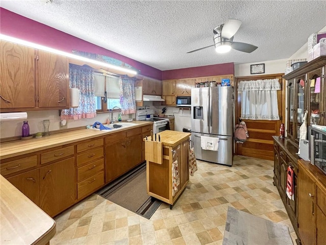 kitchen with ceiling fan, sink, butcher block countertops, a textured ceiling, and appliances with stainless steel finishes