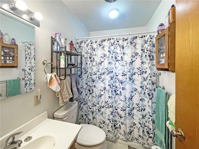 bathroom featuring tile patterned flooring, curtained shower, vanity, and toilet