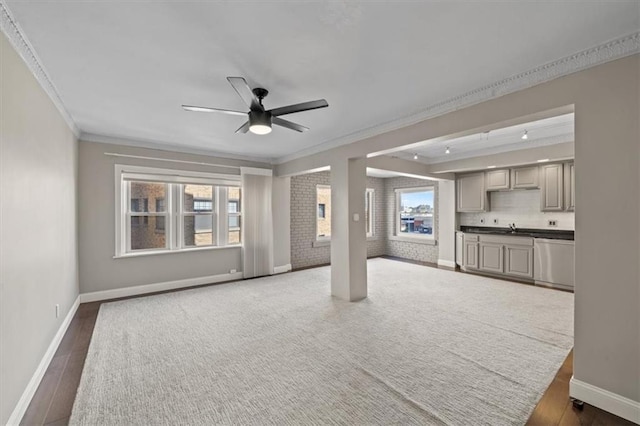 unfurnished living room featuring ceiling fan, ornamental molding, sink, and dark hardwood / wood-style flooring