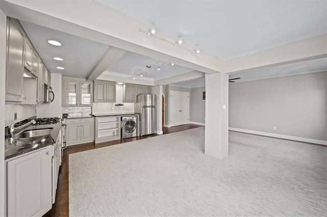 kitchen featuring washer / dryer, sink, beam ceiling, stainless steel appliances, and backsplash