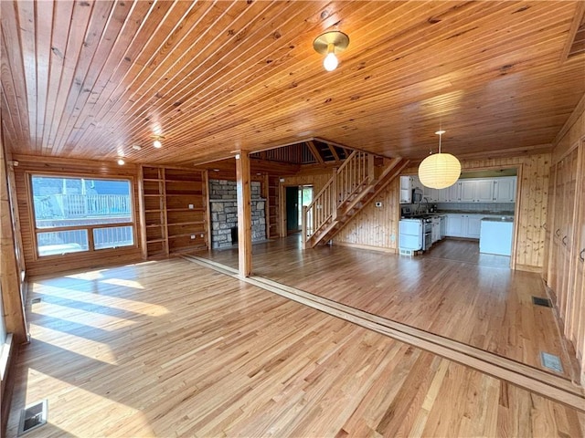 27 Beach Dr, Lake Tapawingo, MO 64015 - unfurnished living room with wood walls, wood-type flooring, wooden ceiling, stairway, and a fireplace
