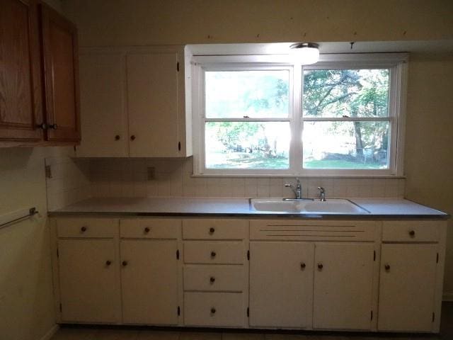 kitchen featuring white cabinets, backsplash, and sink