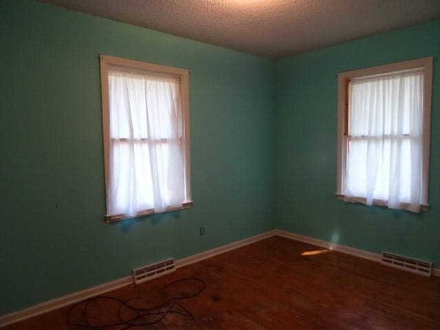 unfurnished room featuring a textured ceiling and hardwood / wood-style floors