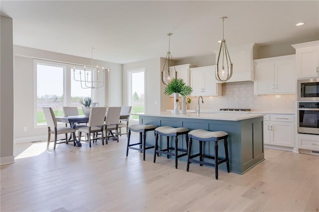 2202 W 178th Ter, Overland Park, KS 66085 - kitchen featuring stainless steel appliances, backsplash, a center island with sink, light countertops, and white cabinets