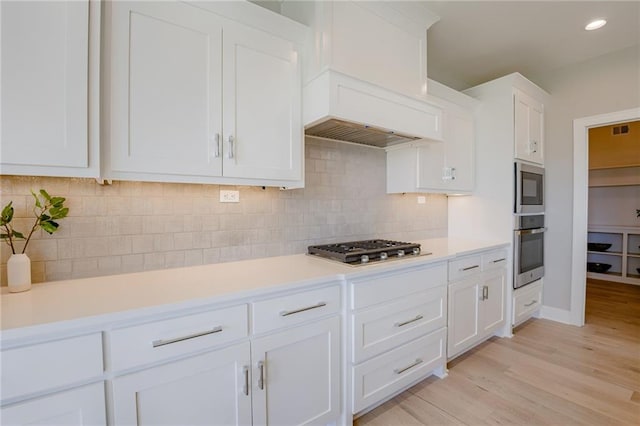 2202 W 178th Ter, Overland Park, KS 66085 - kitchen featuring white cabinetry, light countertops, light wood-style flooring, appliances with stainless steel finishes, and backsplash