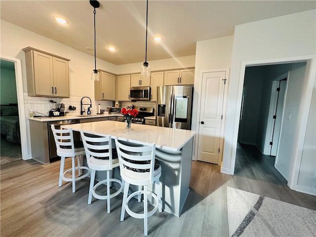 kitchen with pendant lighting, a center island, decorative backsplash, stainless steel appliances, and hardwood / wood-style floors