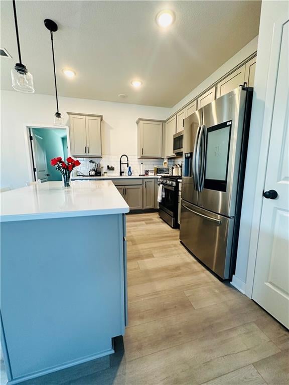 kitchen featuring decorative light fixtures, gray cabinets, appliances with stainless steel finishes, and light hardwood / wood-style floors