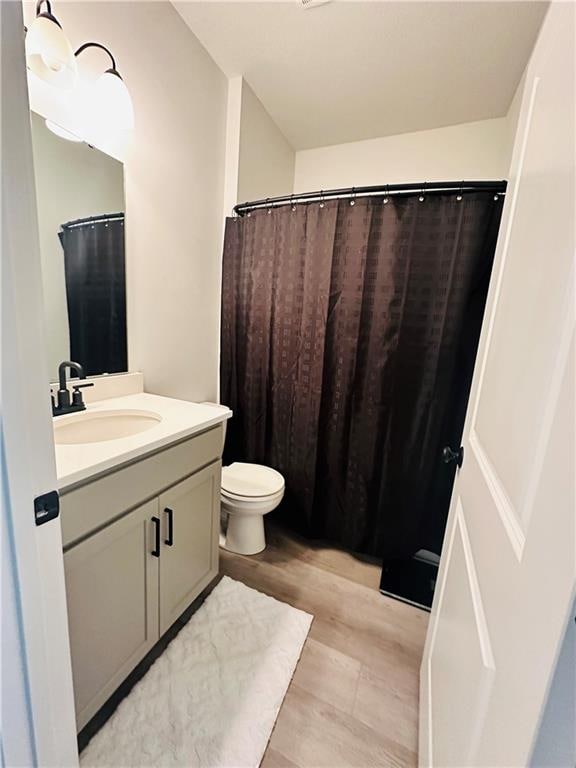 bathroom with toilet, vanity, and hardwood / wood-style floors