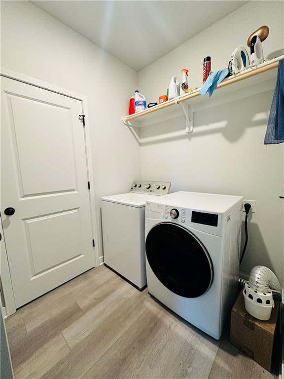 laundry area featuring washing machine and clothes dryer and light hardwood / wood-style flooring