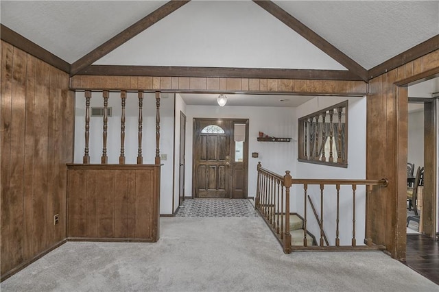 carpeted entryway featuring vaulted ceiling with beams and wood walls