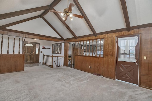 interior space with wood walls, beamed ceiling, and ceiling fan