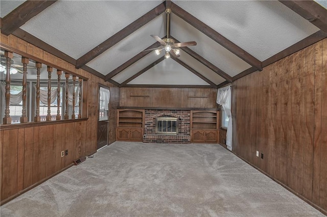 unfurnished living room with wooden walls, lofted ceiling with beams, light colored carpet, and ceiling fan