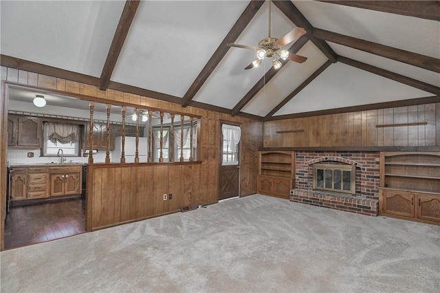 unfurnished living room featuring vaulted ceiling with beams, carpet, and a wealth of natural light