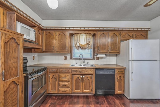 kitchen featuring backsplash, a textured ceiling, dark hardwood / wood-style floors, sink, and white appliances