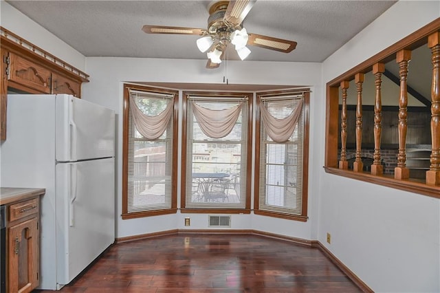 unfurnished dining area featuring ceiling fan, a textured ceiling, and dark hardwood / wood-style floors