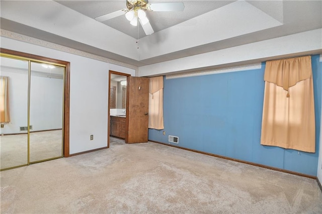 unfurnished bedroom featuring connected bathroom, carpet floors, a closet, and ceiling fan