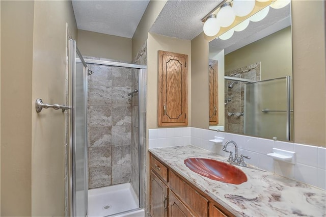 bathroom featuring a shower with door, vanity, a textured ceiling, and backsplash