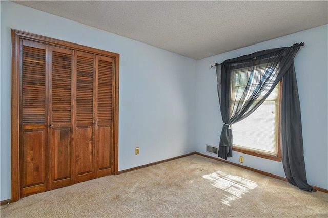 unfurnished bedroom with a closet, a textured ceiling, and light colored carpet