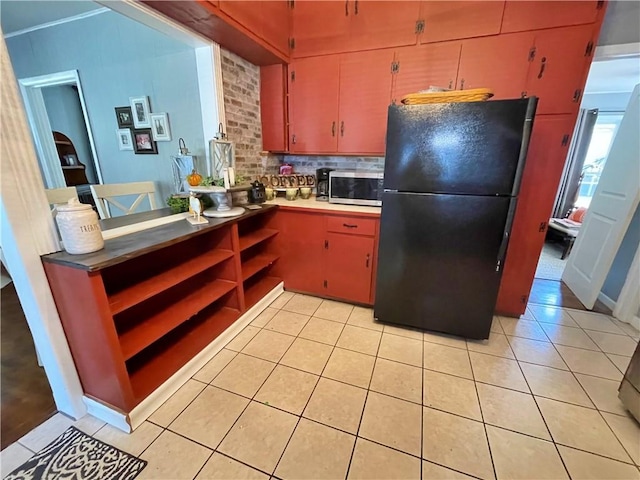 kitchen featuring black refrigerator, light tile patterned flooring, and tasteful backsplash