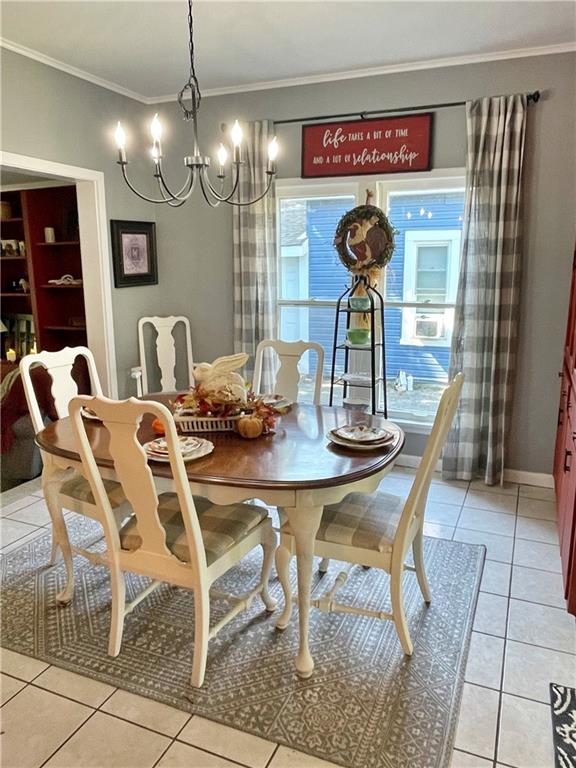 dining space featuring a notable chandelier, light tile patterned floors, and crown molding