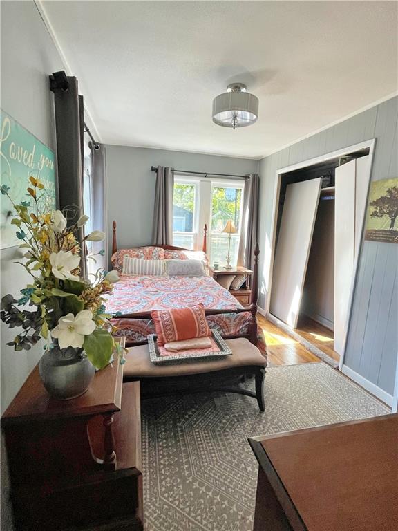 bedroom featuring a closet, wood walls, and light hardwood / wood-style floors