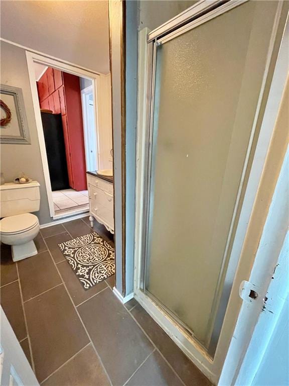 bathroom featuring tile patterned floors, a shower with shower door, and toilet