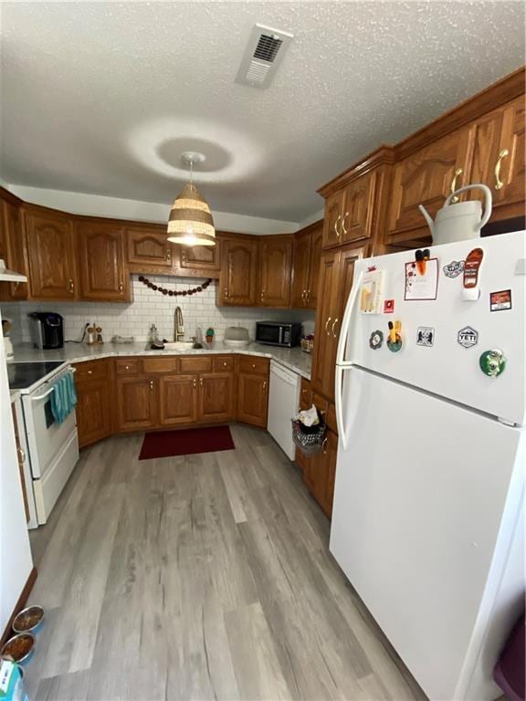 111 W 9th St, Maryville, MO 64468 - kitchen featuring light hardwood / wood-style floors, tasteful backsplash, sink, white appliances, and decorative light fixtures