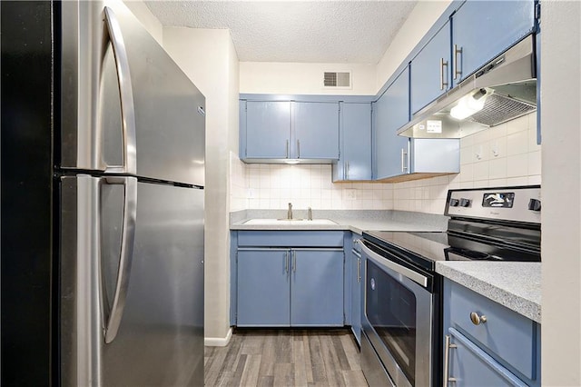 kitchen featuring blue cabinetry, sink, stainless steel appliances, dark hardwood / wood-style flooring, and a textured ceiling