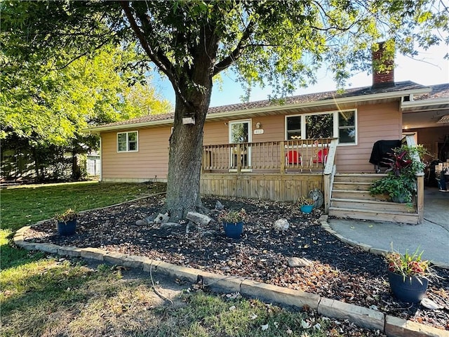 view of front facade featuring a wooden deck and a front yard