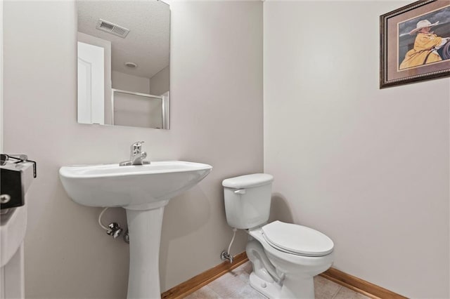 bathroom featuring tile patterned flooring, a textured ceiling, and toilet