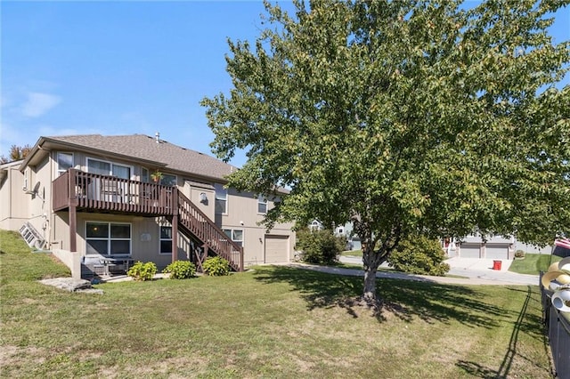 rear view of property featuring a lawn, a garage, and a deck