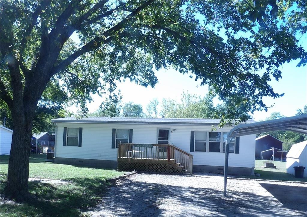 manufactured / mobile home featuring a front yard and a carport