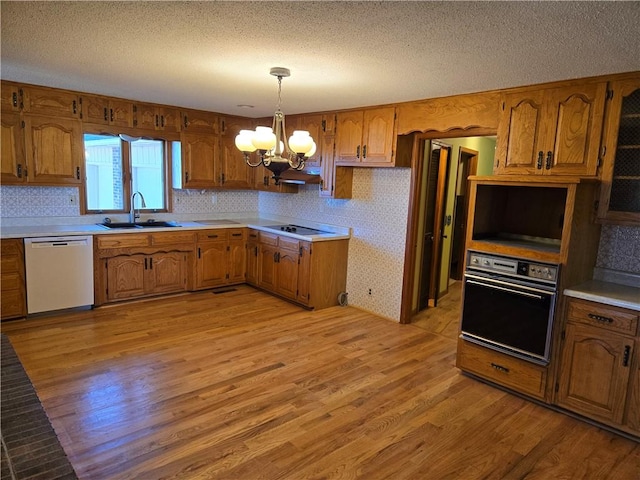 kitchen with pendant lighting, sink, oven, dishwasher, and light hardwood / wood-style floors